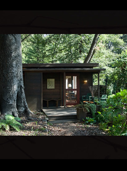 Studio cottage with its private porch surrounded by large tree and wooded area.