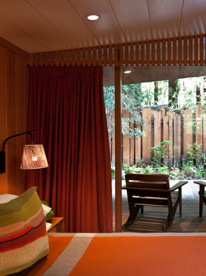 View of bed facing outdoors with wooden chairs and privacy fence.