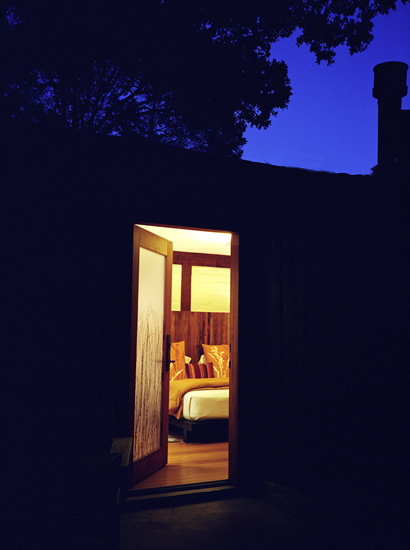 Outdoor view of Fireside Lodge King at night with an open door leading into the lit room with a view of the bed.