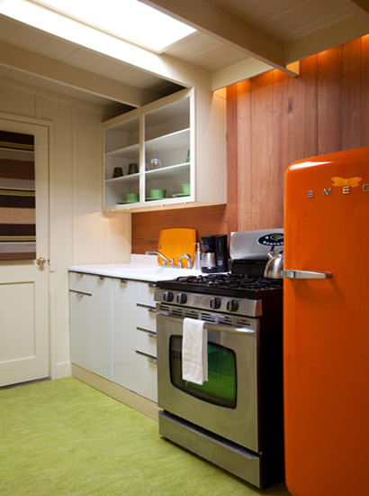 Kitchen featuring a retro enamel sink and countertop with a modern stainless gas range, microwave, coffee maker and stylish orange refrigerator.