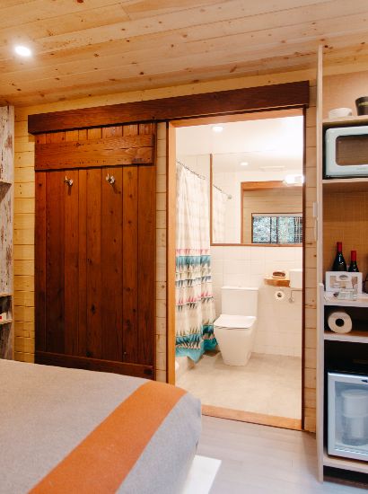 View into the bathroom from the foot of the bed with kitchenette pictured to the right.