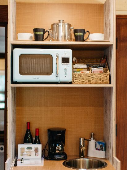 Efficient kitchenette with a sink, cooler, microwave and coffee maker.