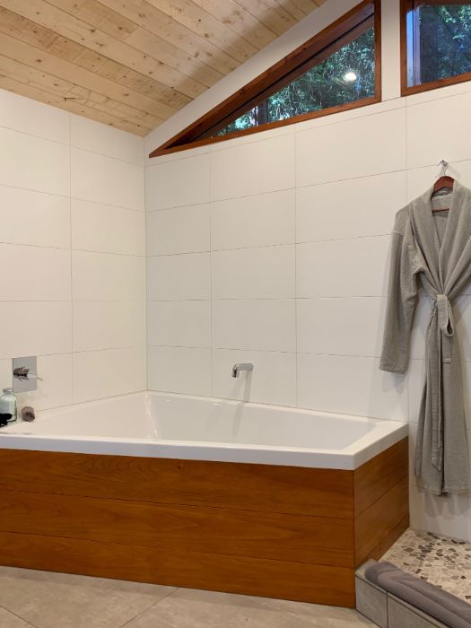 Oversized tub large enough for two, robe hanging on the wall, and luxurious heated tile floor.