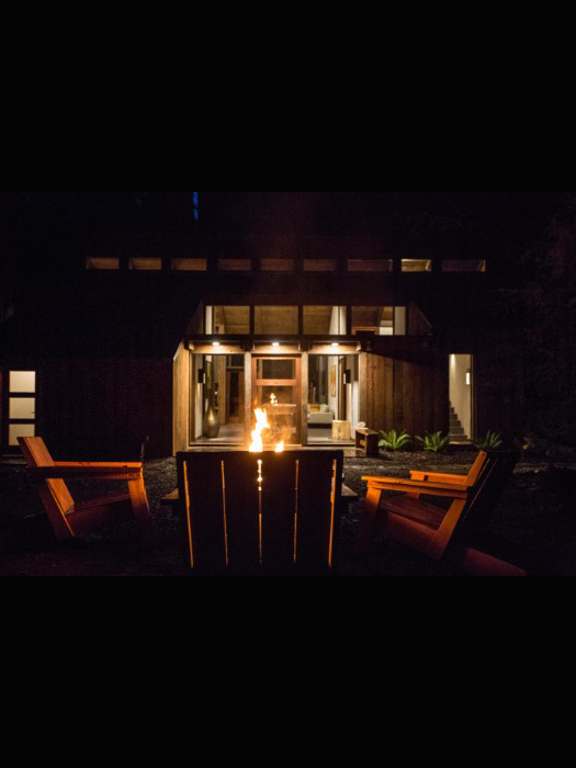 Outdoor sitting area in front of the cabin with fire pit at night.